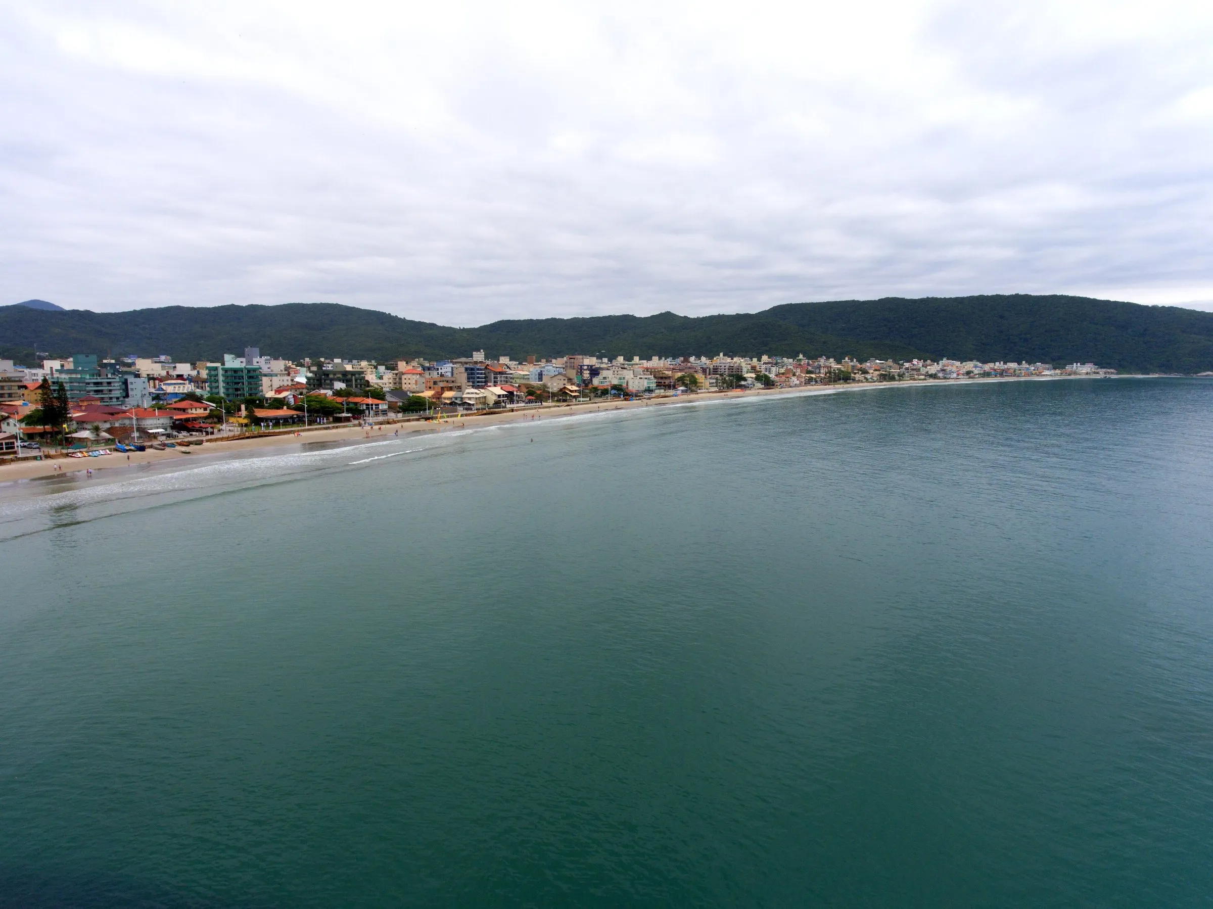 La curva de la playa de Bombas vista desde el mar, con edificios y morros al fondo